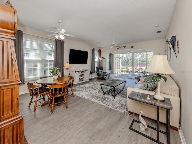 living room with ceiling fan, a healthy amount of sunlight, and light wood-type flooring