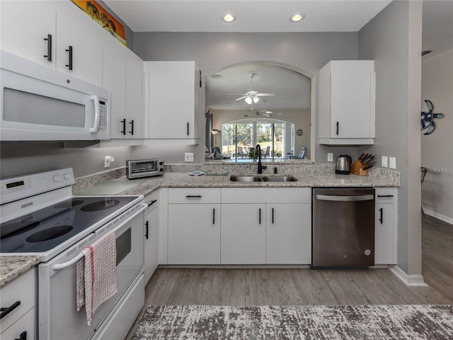 kitchen with sink, white appliances, light hardwood / wood-style flooring, ceiling fan, and white cabinetry