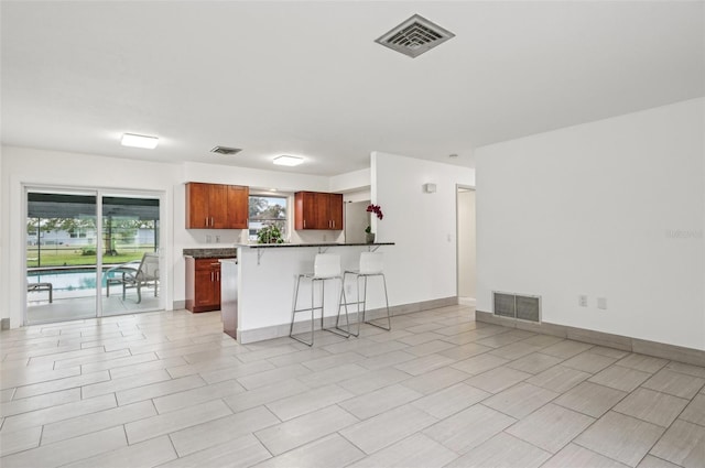 kitchen with a breakfast bar area, kitchen peninsula, and a healthy amount of sunlight