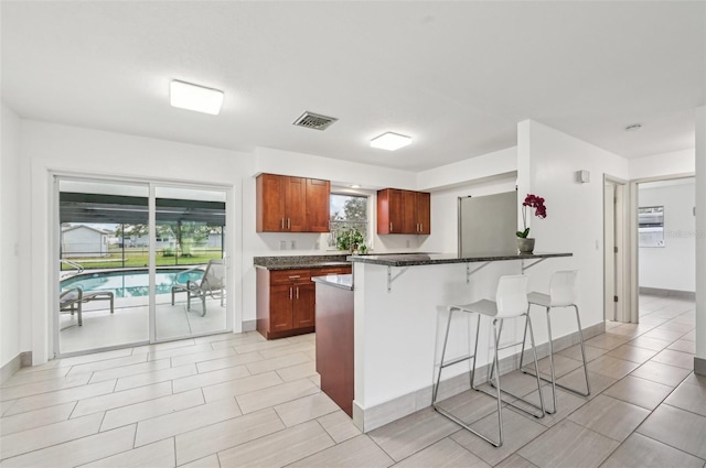 kitchen featuring dark stone countertops, a breakfast bar area, and stainless steel fridge