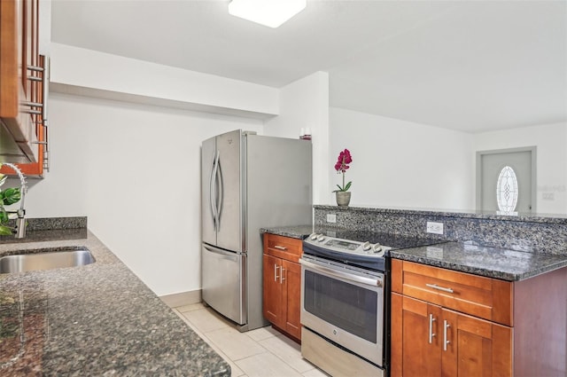 kitchen with appliances with stainless steel finishes, light tile patterned floors, and dark stone countertops