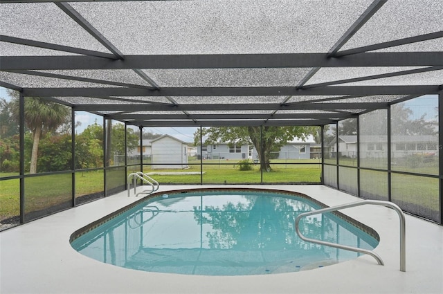 view of swimming pool featuring glass enclosure and a lawn