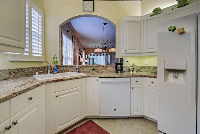 kitchen with sink, light stone counters, a notable chandelier, white appliances, and white cabinets