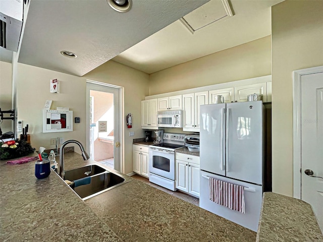 kitchen featuring sink, white cabinets, and white appliances