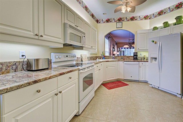 kitchen with light tile patterned flooring, white cabinetry, sink, light stone countertops, and white appliances