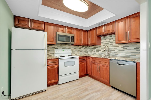 kitchen with stainless steel appliances, a raised ceiling, sink, and backsplash