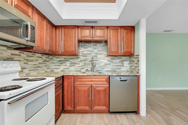 kitchen with light stone counters, sink, decorative backsplash, and appliances with stainless steel finishes