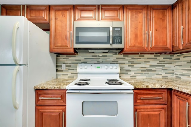 kitchen with light stone counters, backsplash, and white appliances