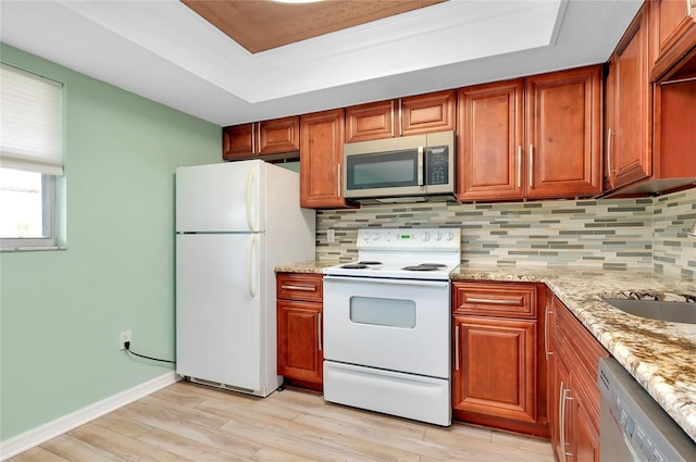 kitchen with sink, light stone counters, light hardwood / wood-style flooring, stainless steel appliances, and decorative backsplash