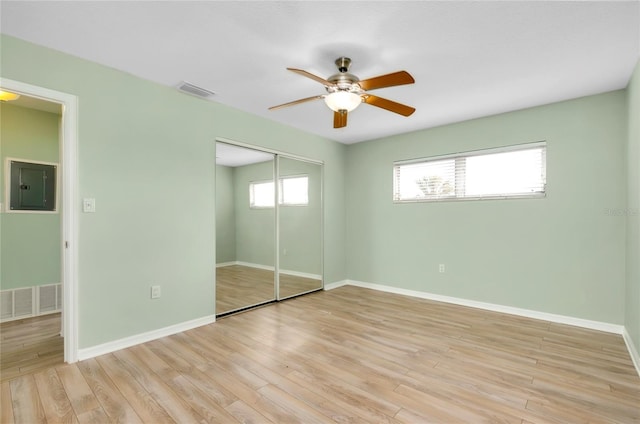 unfurnished bedroom with electric panel, a closet, ceiling fan, and light wood-type flooring