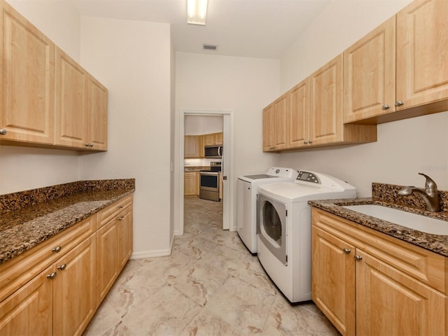 clothes washing area featuring sink, cabinets, and independent washer and dryer