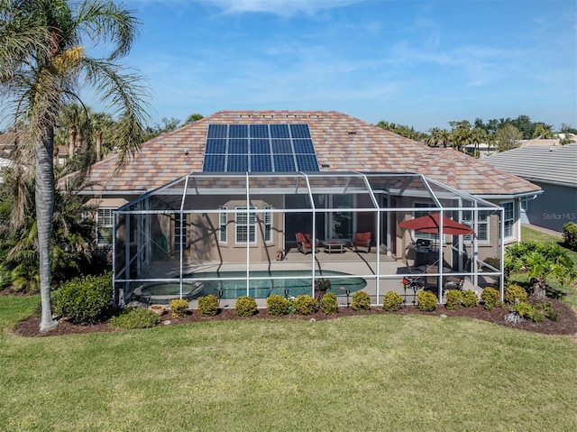 rear view of property with a yard, a lanai, a patio area, and solar panels