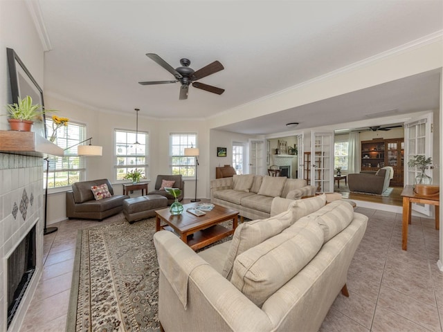 tiled living room with a tiled fireplace, ornamental molding, and ceiling fan