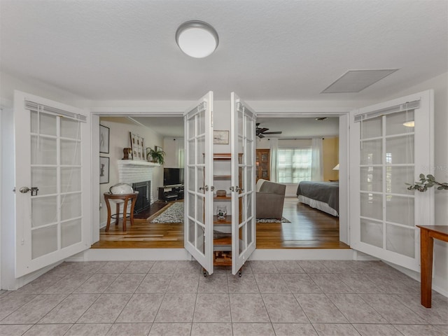 interior space with french doors, a textured ceiling, and light tile patterned floors