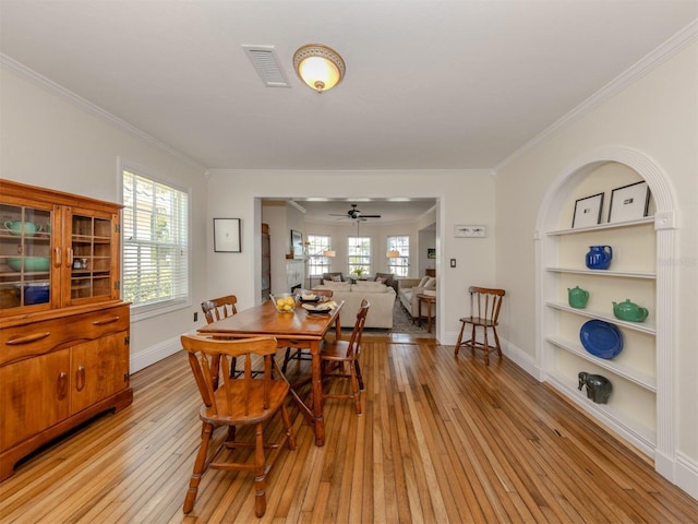 dining room featuring ceiling fan, ornamental molding, light hardwood / wood-style floors, and built in features