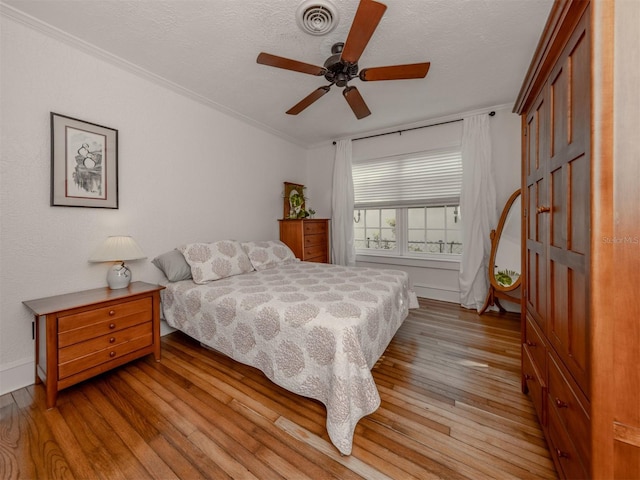 bedroom with crown molding, a textured ceiling, light hardwood / wood-style floors, and ceiling fan