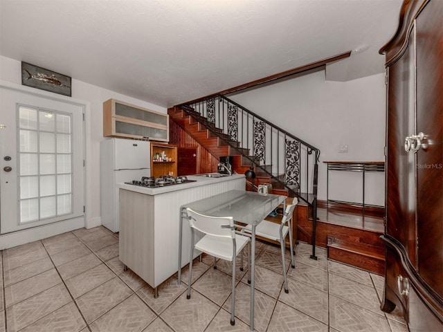 kitchen featuring kitchen peninsula, sink, white fridge, and gas stovetop