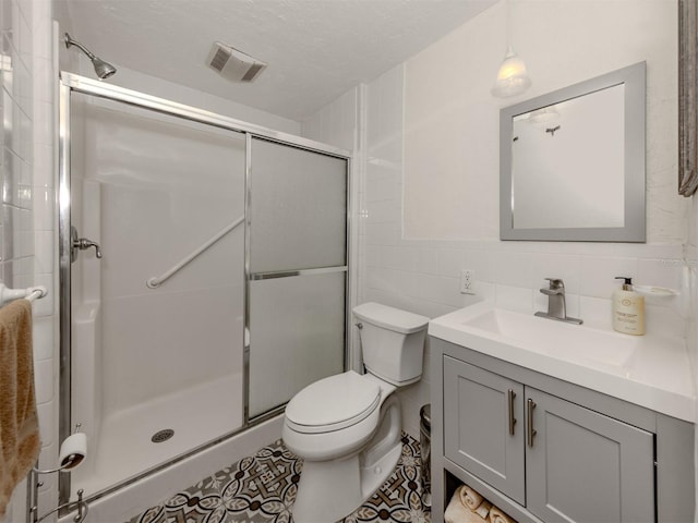 bathroom with toilet, an enclosed shower, tile walls, a textured ceiling, and vanity