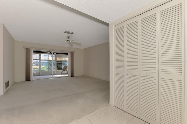 unfurnished bedroom featuring light colored carpet, a textured ceiling, ceiling fan, and a closet