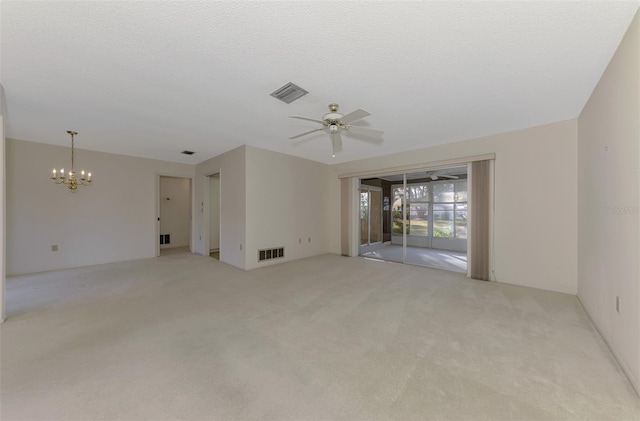 carpeted spare room with ceiling fan with notable chandelier and a textured ceiling