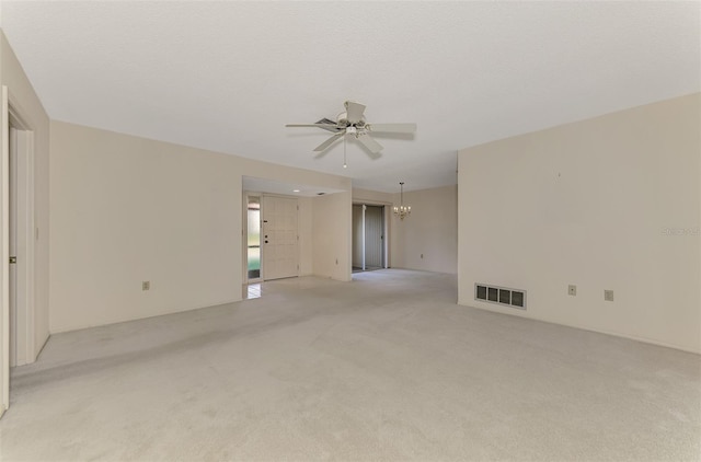 carpeted spare room with ceiling fan with notable chandelier and a textured ceiling