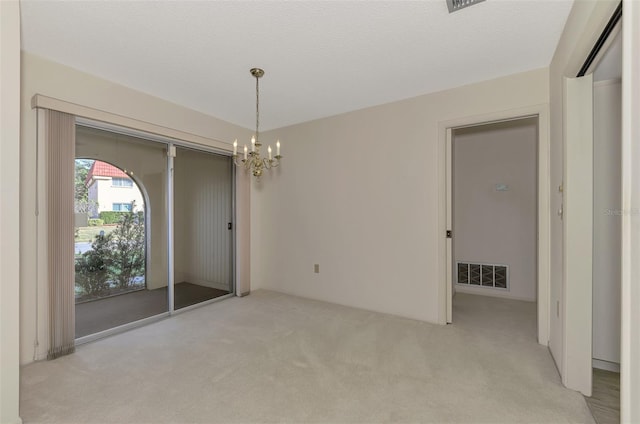 carpeted spare room with a chandelier