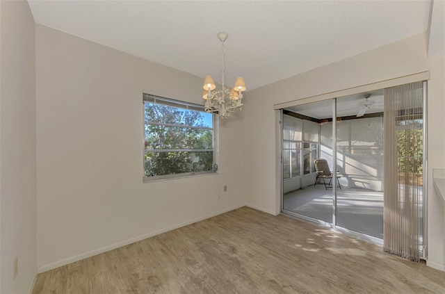 empty room with wood-type flooring, a notable chandelier, and a textured ceiling