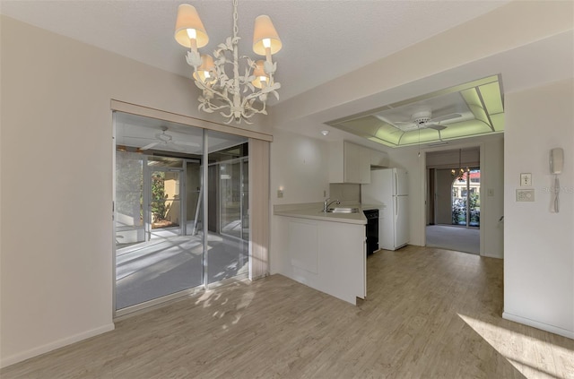 interior space with sink, light hardwood / wood-style flooring, a textured ceiling, a raised ceiling, and ceiling fan with notable chandelier