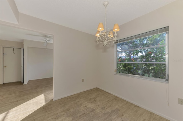 spare room with an inviting chandelier and hardwood / wood-style flooring