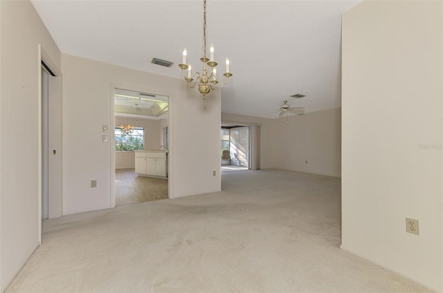 unfurnished room featuring ceiling fan with notable chandelier and light colored carpet