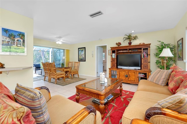 living area featuring light tile patterned floors, visible vents, a ceiling fan, and baseboards