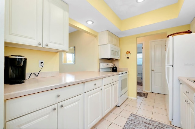 kitchen with kitchen peninsula, white cabinets, light tile patterned floors, a tray ceiling, and white appliances