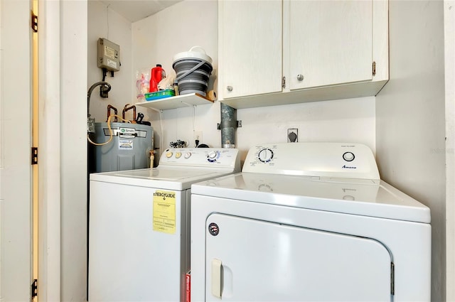 clothes washing area with cabinets, washing machine and clothes dryer, and water heater