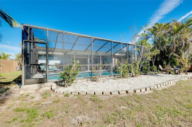 rear view of property with a yard and glass enclosure