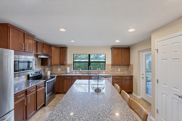 kitchen with a kitchen bar, sink, tasteful backsplash, appliances with stainless steel finishes, and dark stone counters