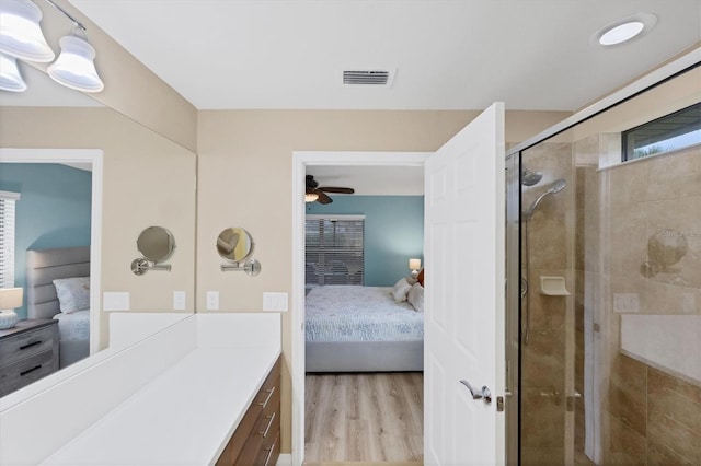 bathroom featuring ceiling fan, vanity, an enclosed shower, and hardwood / wood-style floors