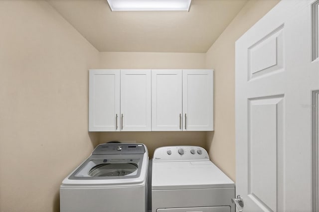 laundry room with separate washer and dryer and cabinets