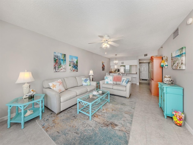 living room with ceiling fan and a textured ceiling