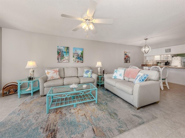 living room with ceiling fan with notable chandelier and a textured ceiling