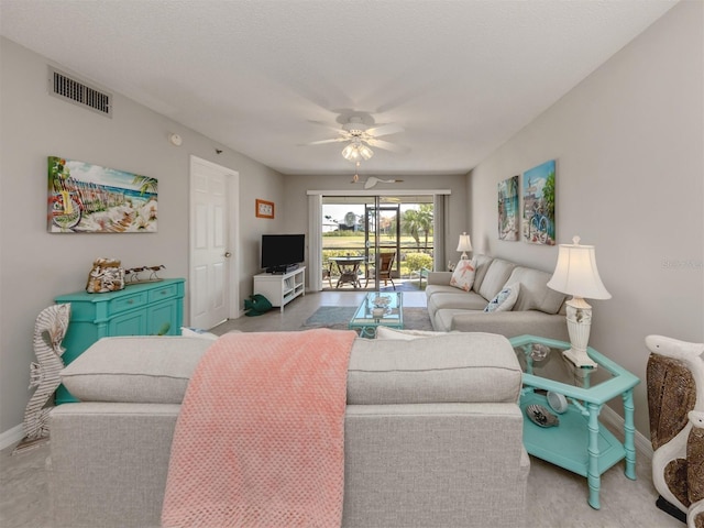 living room featuring ceiling fan and a textured ceiling