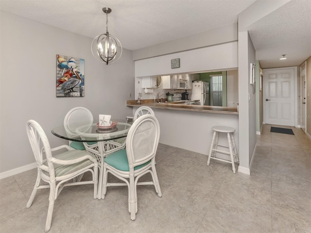 dining room featuring sink, a chandelier, and a textured ceiling