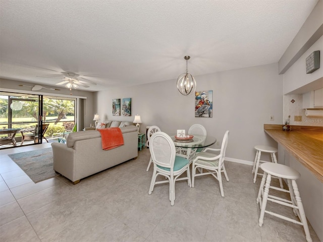 tiled dining space featuring ceiling fan with notable chandelier and a textured ceiling