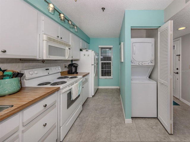 kitchen with stacked washer and clothes dryer, a textured ceiling, white cabinets, and white appliances