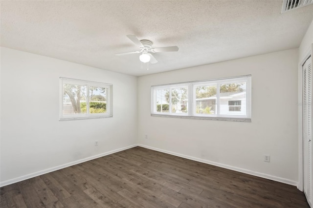 empty room with ceiling fan, dark hardwood / wood-style flooring, and a textured ceiling