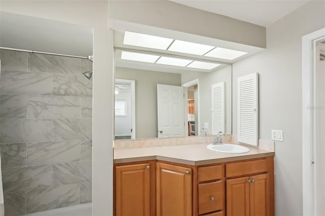 bathroom with vanity, a skylight, and a tile shower