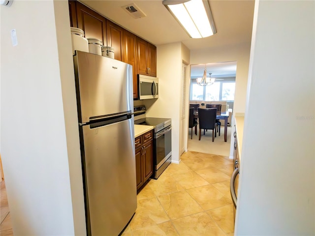 kitchen featuring stainless steel appliances, light tile patterned flooring, and an inviting chandelier