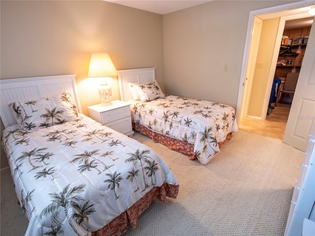 bedroom featuring a walk in closet, light colored carpet, and a closet