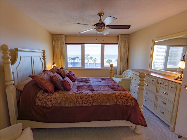 bedroom with ceiling fan, light colored carpet, and a textured ceiling