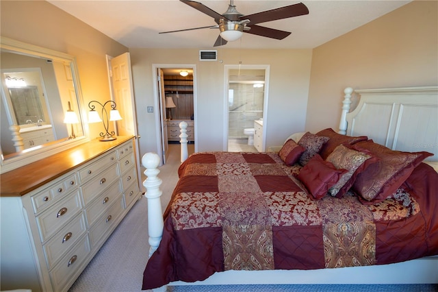 carpeted bedroom featuring ceiling fan, a closet, ensuite bath, and a walk in closet