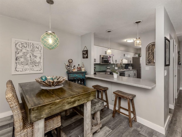 dining space with a textured ceiling, baseboards, and wood finished floors